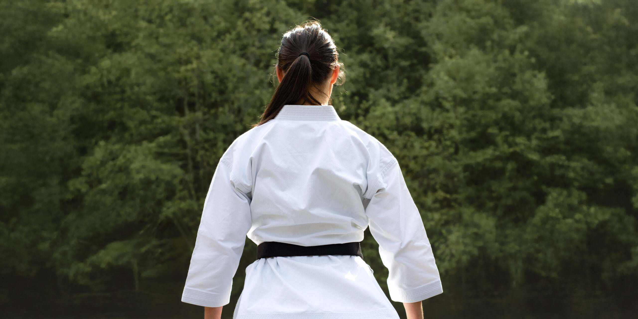Une femme en kimono de dos avec sa ceinture noire de karaté