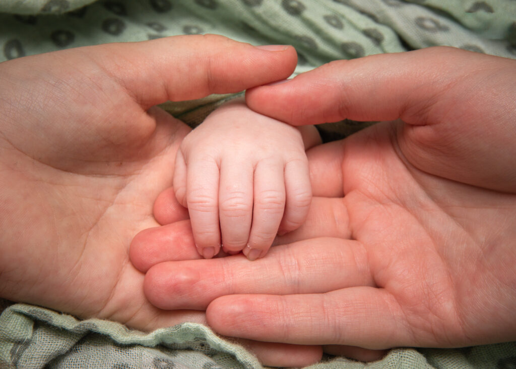 Photographie des détails d'une main d'un bébé avec celles de ses parents en Alsace