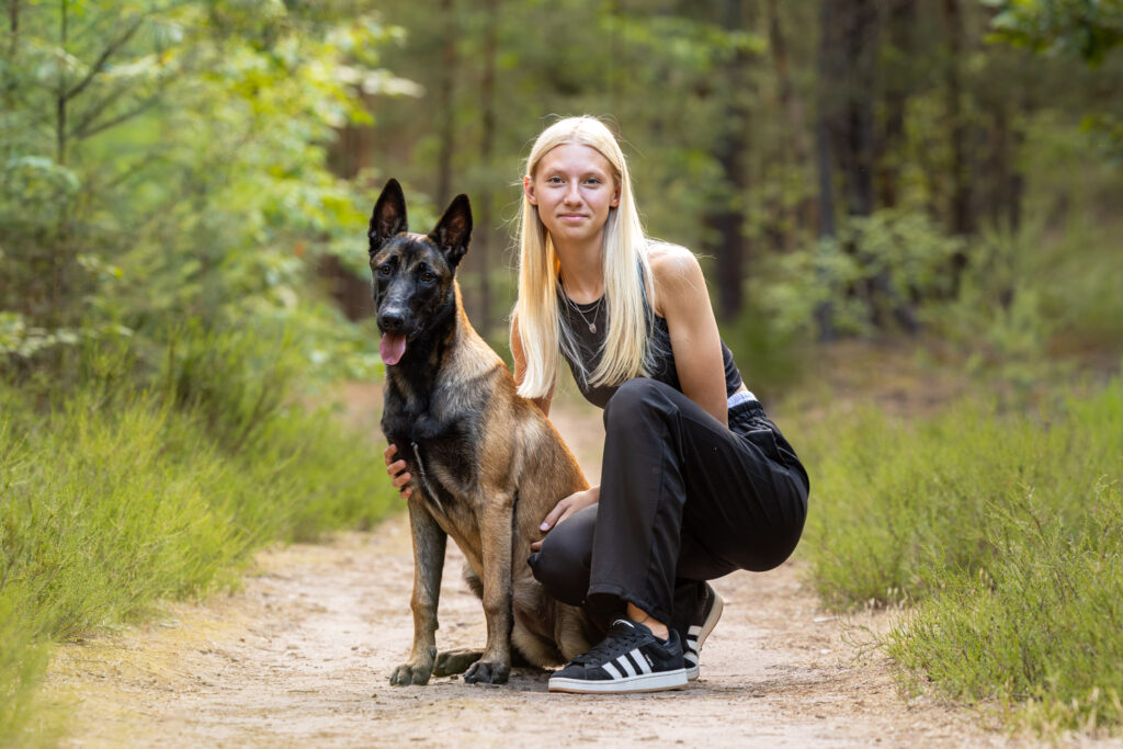 Photographie de la complicité entre un chiot malinois et son maître dans la forêt
